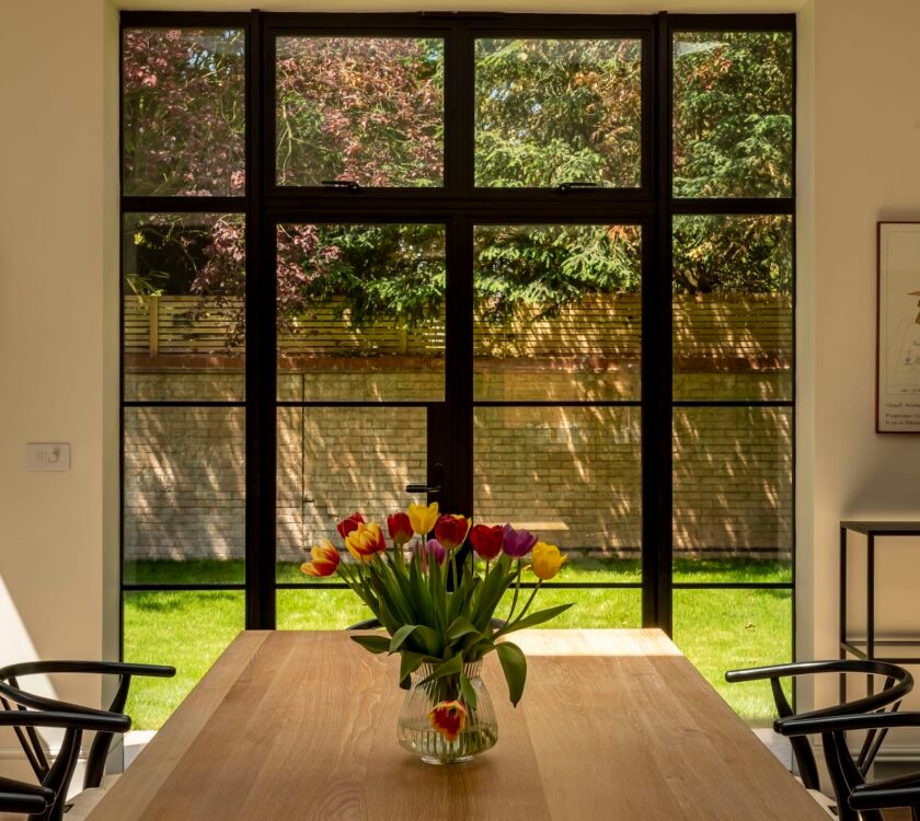 picture of kitchen patio doors in the steel look design, black colour with dining table in foreground