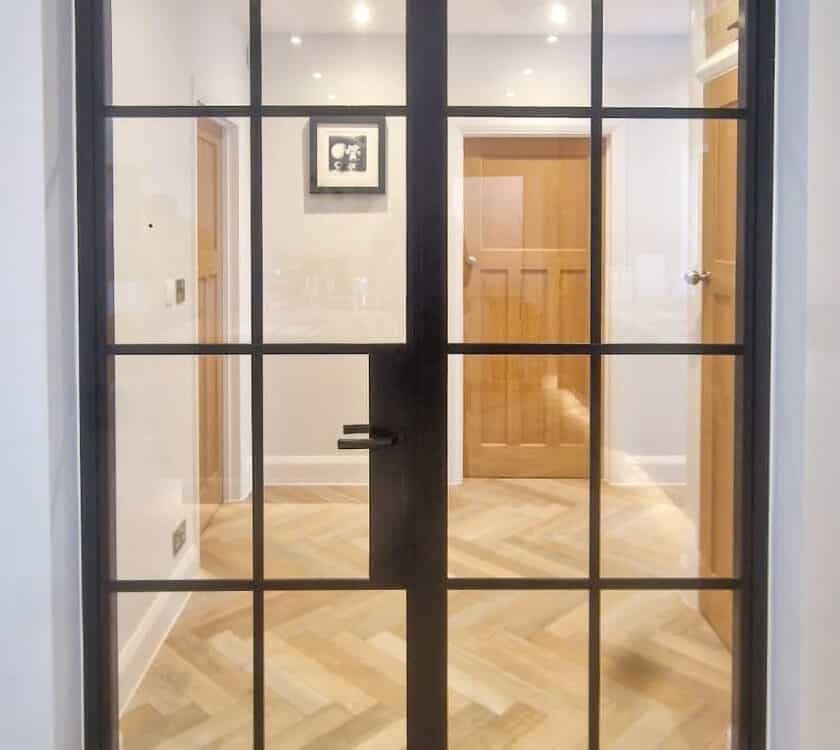 internal metal style doors with wood flooring separating kitchen and hallway