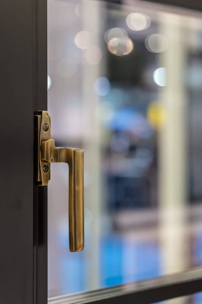 brass designer window handle on a black window frame.