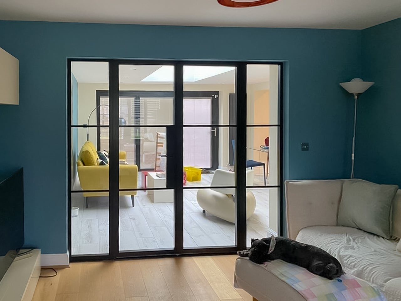 aluco internal black metal internal doors separating a lounge and playroom, dog on sofa