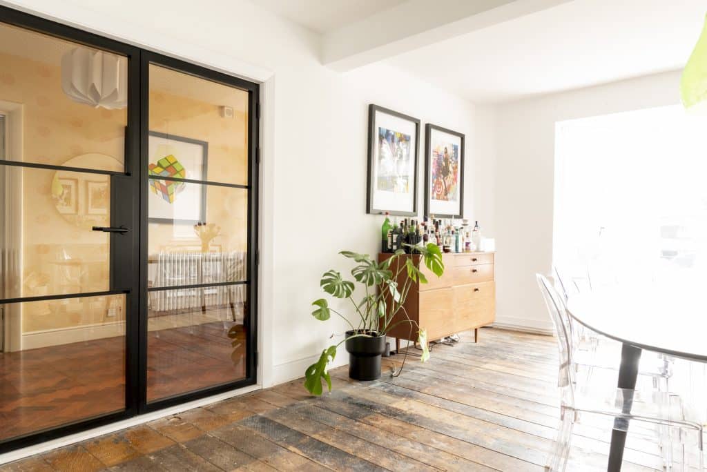 Black Aluco heritage doors in a stylish dining room with wood floor and mini bar