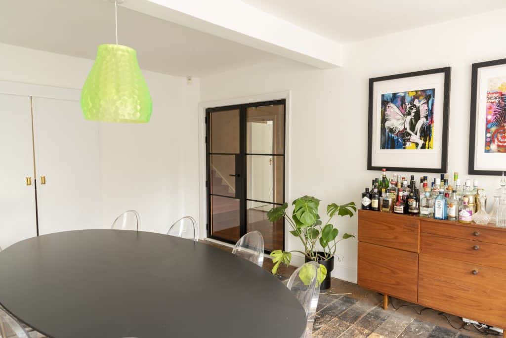 side view of Black Aluco heritage doors in a stylish dining room with wood floor and mini bar