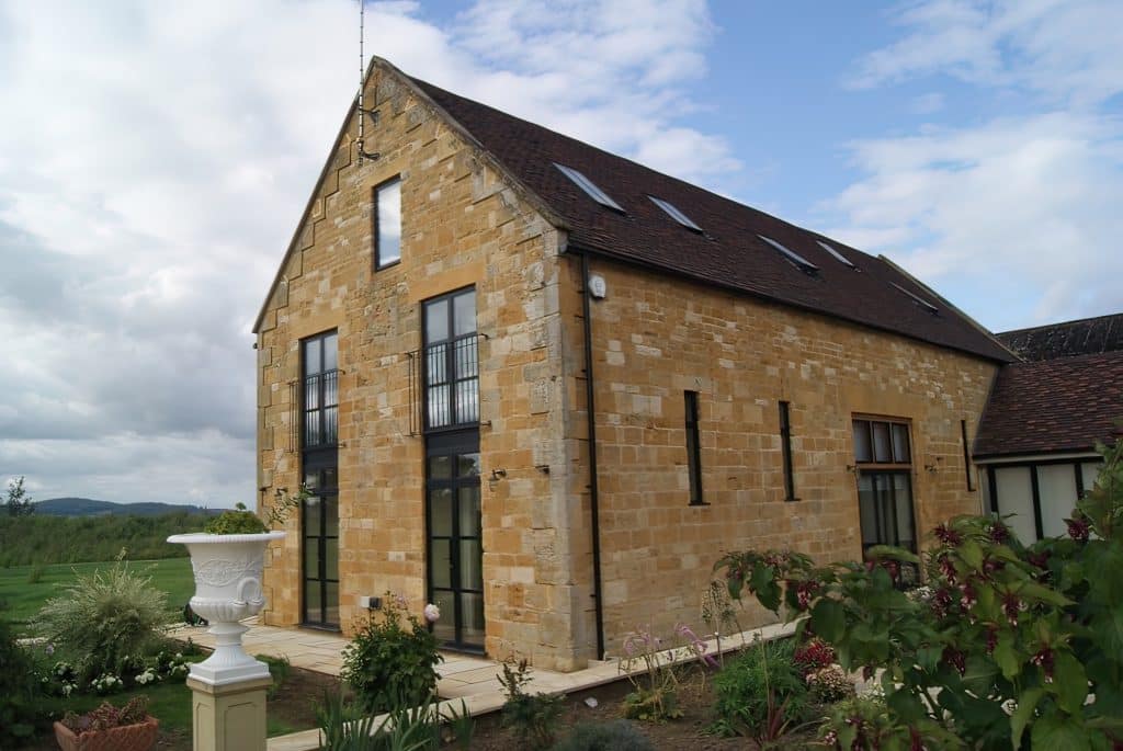 side view of steel look french doors on the side of a stone barn