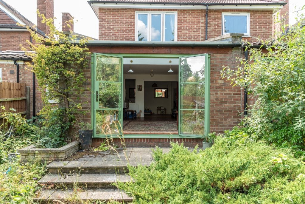external view of green aluco steel look doors in cambridge to a new extension, both doors open