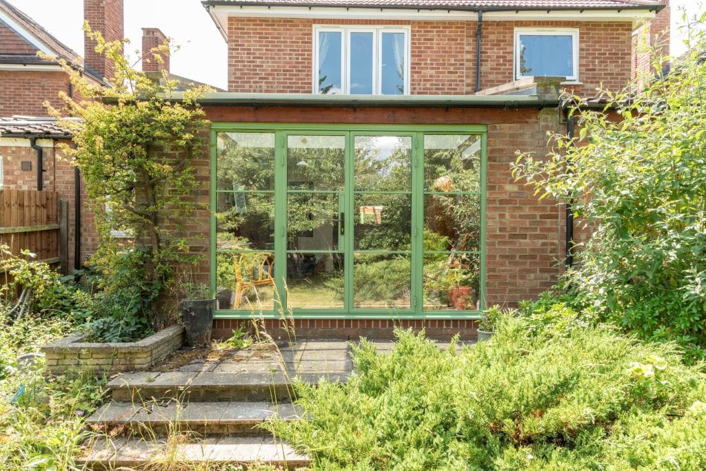 both doors close on external view of green aluco steel look doors in cambridge to a new extension