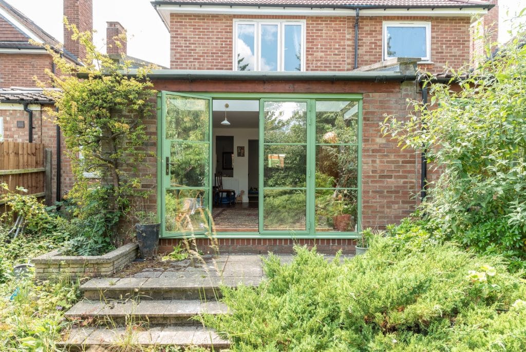 external view of green aluco steel look doors in cambridge to a new extension one door open