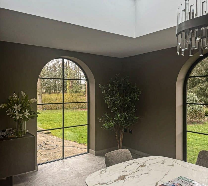 curved aluminium windows in a stylish dining room with lantern roof above.
